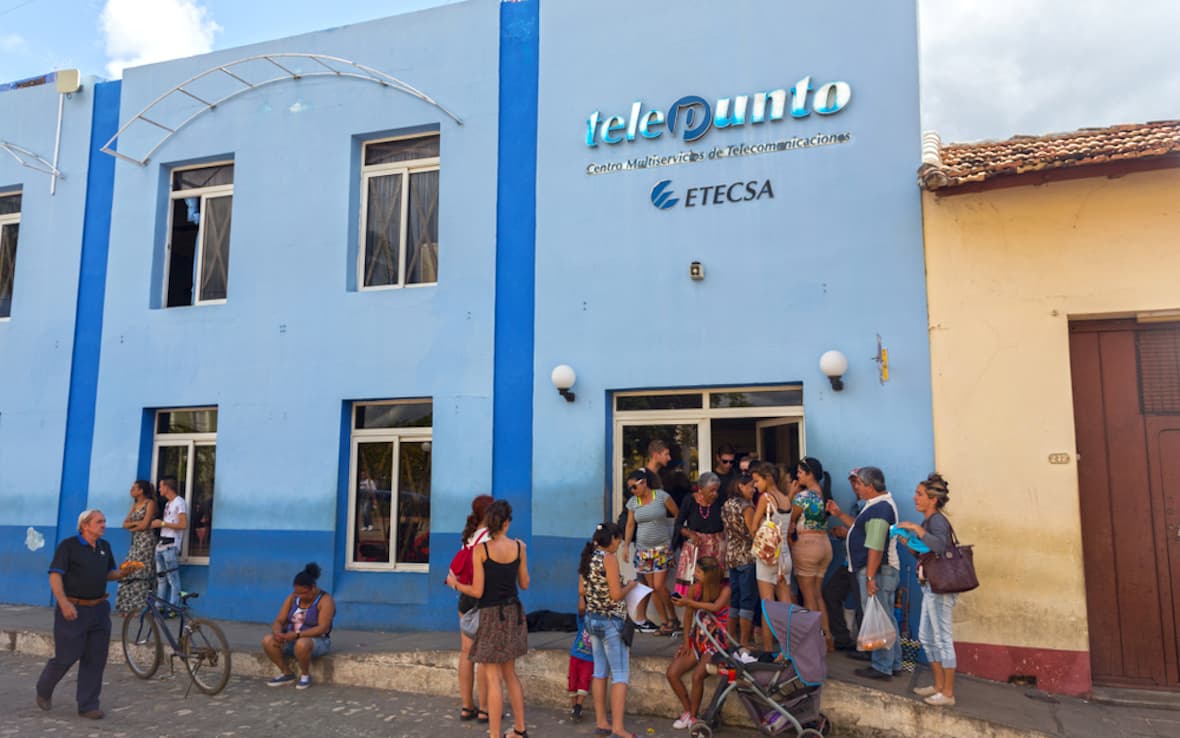 キューバ政府の制御されたETECSA通信会社オフィスの入り口で並んで待っている観光客と地元のキューバ人。
